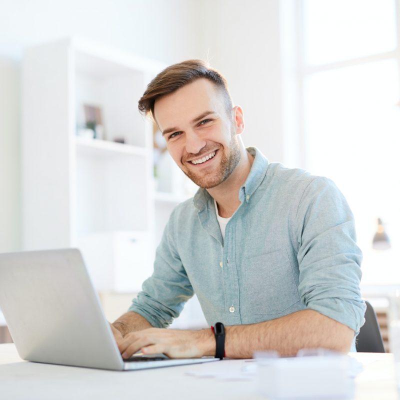 Smiling Young Man Using Laptop